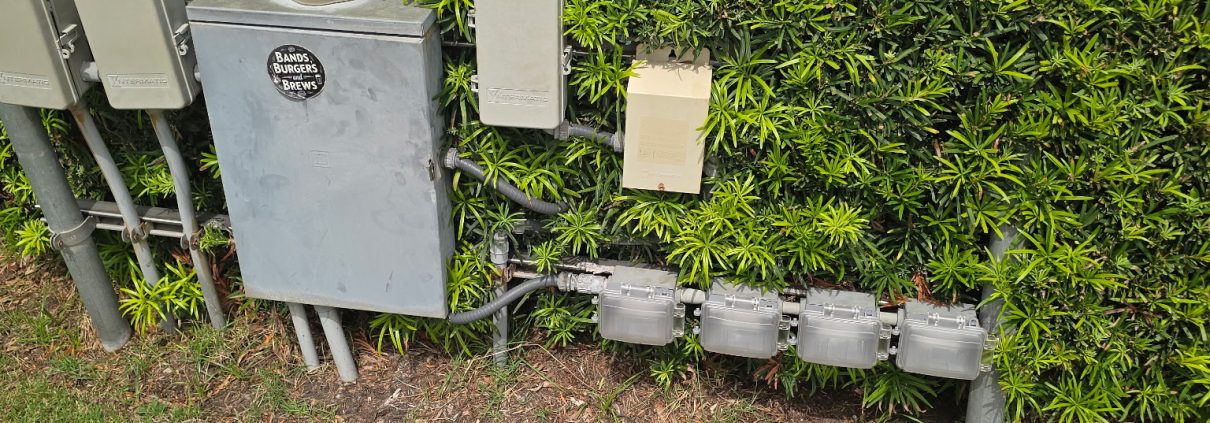 Electrical meter bank and utility boxes serviced by H3 Industries at a commercial property in Palm Beach Gardens