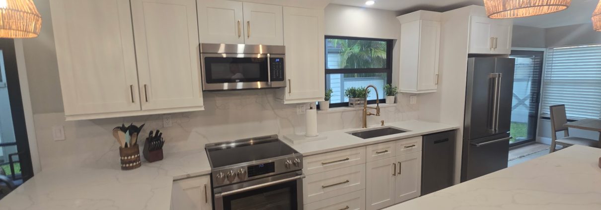 Remodeled kitchen with white cabinets, marble-look countertops and stainless steel appliances by H3 Industries in Palm Beach Gardens