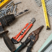 Drywall tools and metal framing materials, including a drill, tin snips, tape measure and level, for plasterboard wall work by H3 Industries in Palm Beach Gardens